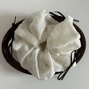 Detail of white chiffon oversized scrunchie with black ribbon bow on wooden tray
