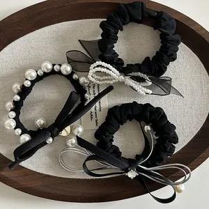 Dettaglio di elastici neri per capelli con perle eleganti e fiocchi decorativi