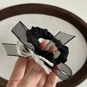 Elegante elastico per capelli con fiocco di perle, nastro nero e ciondolo dorato