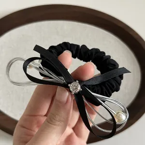 Dettaglio di elastico nero per capelli con fiocco di raso, strass e perla sintetica