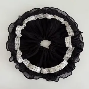 Close-up of black pleated chiffon hair scrunchie with white lace trim in Gothic style