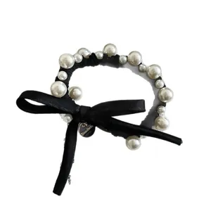 Elegante elastico per capelli nero con perle e fiocco di raso su sfondo bianco