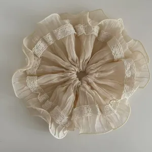 Detailed close-up of beige ruffled scrunchie featuring elegant lace trim and layered mesh