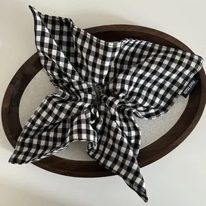 Detail of handcrafted black and white gingham fabric scrunchie with handmade woven label
