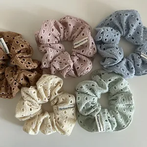 Detailed view of five hollow-out knit scrunchies in pastel colors with Happy labels