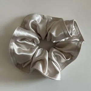 Dettaglio dell'elastico in raso champagne che mostra texture lucida e cucitura fine