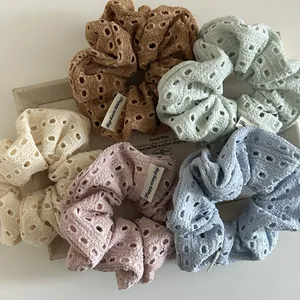 Detailed macro of five colorful hollow-out knit scrunchies with 'Happy every day' labels
