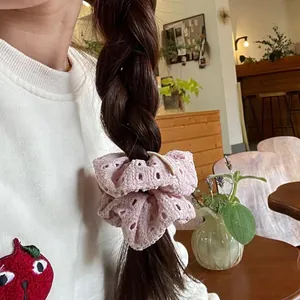 Detail of light pink eyelet lace scrunchie on a braid in a warm cafe setting