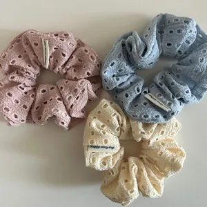 Close-up of knit floral scrunchies in pink, blue and yellow with 'Happy' labels