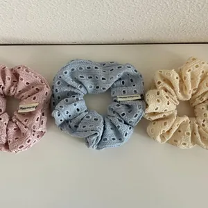 Detailed view of three hollow fabric scrunchies in pink, blue and beige colors