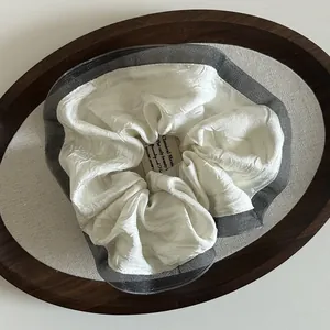Detail of pleated fabric hair scrunchie with lace edge on a wooden tray
