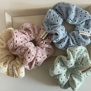Detailed view of floral hollow scrunchies in pastel colors with Happy Every Day woven labels