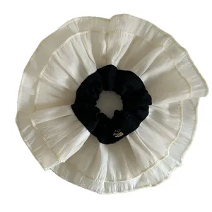 Oversized double-layered lace hair scrunchie in black and white ballet style with gold tag