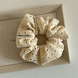 Close-up of cream floral crochet scrunchie with Happy every day fabric label detail