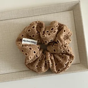Close-up of beige floral hollow lace hair scrunchie with a Happy Every Day fabric tag