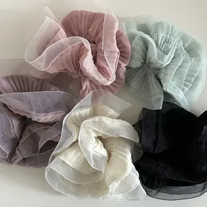 Close-up of pleated organza scrunchies in pastel pink, mint green, and purple