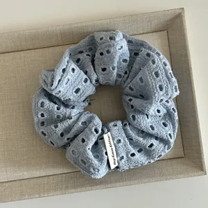 Detail of light blue hollow knit scrunchie with Happy every day woven label
