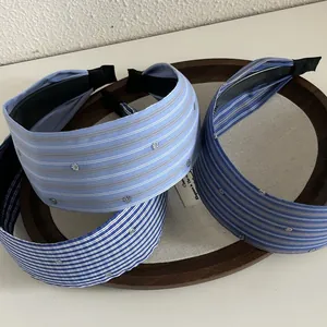 Three blue striped wide fabric headbands with silver rhinestones on a wooden tray