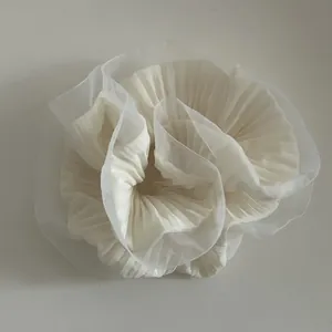 Macro view of ivory ruffled organza hair scrunchie with layered fabric texture