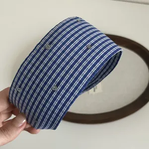Detailed close-up of blue striped wide headband with sparkling silver star sequins