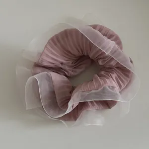 Detail of pink pleated organza scrunchie featuring ruffled white translucent edges