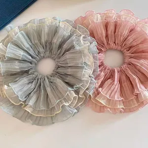 Detailed close-up of oversized layered chiffon hair scrunchies in pastel pink and blue