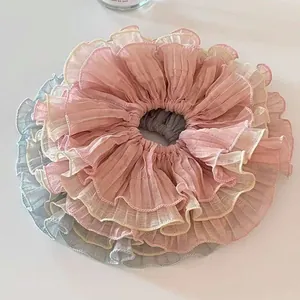 Macro detail of layered chiffon scrunchies with delicate ruffled edges in pastel tones