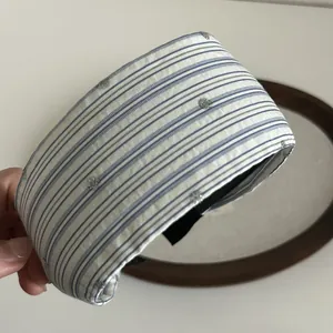Detail of blue striped wide headband with silver glitter dots held by hand