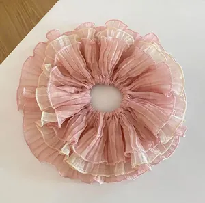 Macro detail of layered pink and beige pleated chiffon lace oversized scrunchie texture