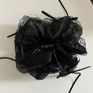 Detail of black organza scrunchie with lace edge and long satin ribbon bows