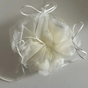 Detailed view of cream organza hair scrunchie with lace edges and satin ribbons
