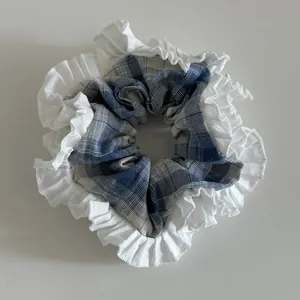 Dettaglio dello scrunchie a scacchi blu con eleganti bordi a balze bianche a doppio strato