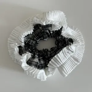 Dettaglio del tessuto a scacchi e bordo in pizzo plissettato bianco su uno scrunchie
