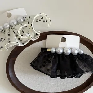 Barrettes en dentelle à pois et perles, styles noir et blanc sur un plateau en bois