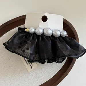 Détail d'une pince à cheveux en tulle à pois avec perles sur un plateau en bois