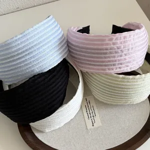 Serre-têtes larges en dentelle pastel empilés sur un plateau rond en bois naturel