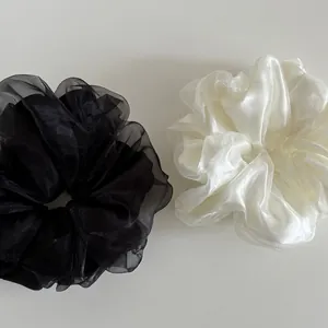 Detail of elegant oversized mesh hair scrunchies in translucent black and cream white