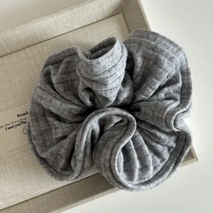 Gros plan sur un chouchou en tricot gris avec texture côtelée douce dans un plateau