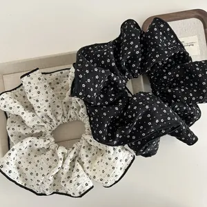 Detail of floral oversized scrunchies in black and white with contrast overlock edge