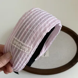 Détail d'un serre-tête en tissu rayé rose et blanc avec broderie en dentelle raffinée