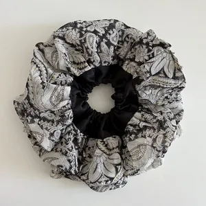 Macro detail of oversized paisley satin scrunchie showing floral pattern and texture