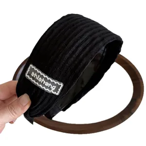 Serre-tête large à rayures noires avec écusson en dentelle sur fond blanc épuré
