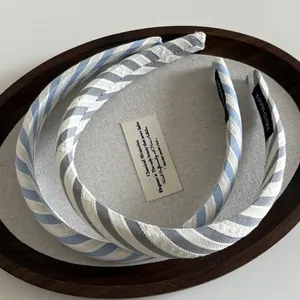 Serre-têtes en tissu rayé bleu et gris dans un plateau bois avec étiquette main