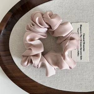 Detalle de elegante coletero de satén rosa pálido con brillo sedoso y textura plisada