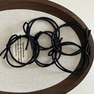 High-elastic black hair ties with bow knot design displayed in a wooden tray