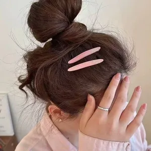 Détail d'une barrette rose en acétate avec texte Barrette La France sur un chignon brun