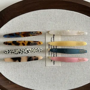 Vue à plat de barrettes en acétate colorées à motifs marbrés sur plateau en lin