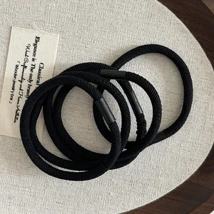 Detailed close-up of high-elasticity black hair ties with matte texture connectors