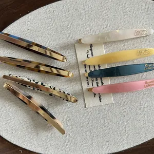 Détail de barrettes colorées en acétate sur tissu en lin vintage avec base en métal doré