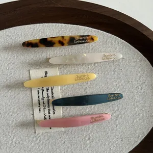 Détail de cinq barrettes en acétate colorées avec boucle métallique et gravure